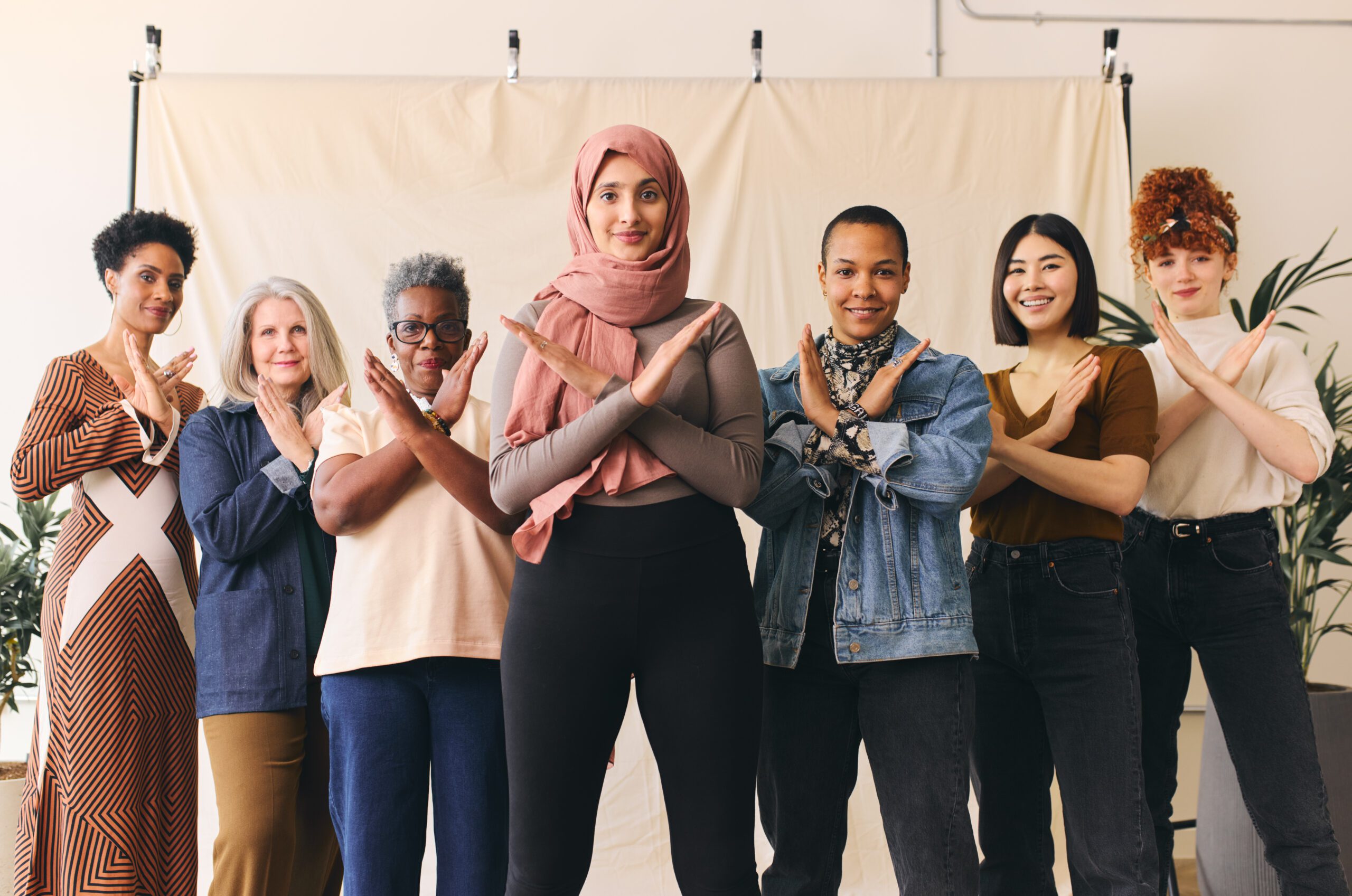 Woman wearing hajib gesturing Break The Bias in support of International Women's Day with female friends.